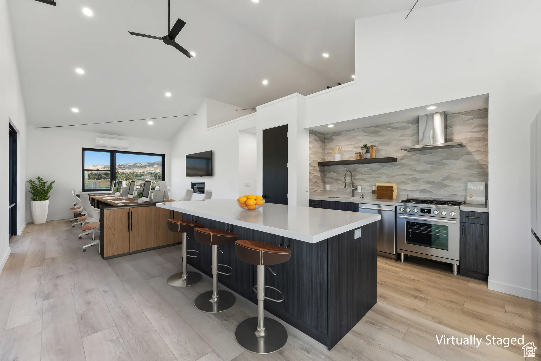 Kitchen featuring high vaulted ceiling, stainless steel appliances, light wood-type flooring, a large island, and wall chimney range hood