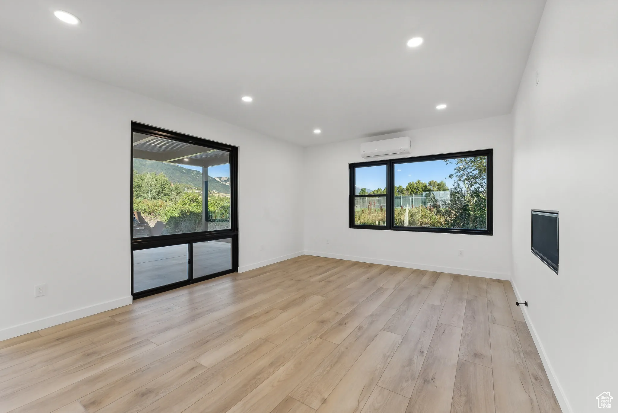 Spare room featuring an AC wall unit, light hardwood / wood-style flooring, and plenty of natural light