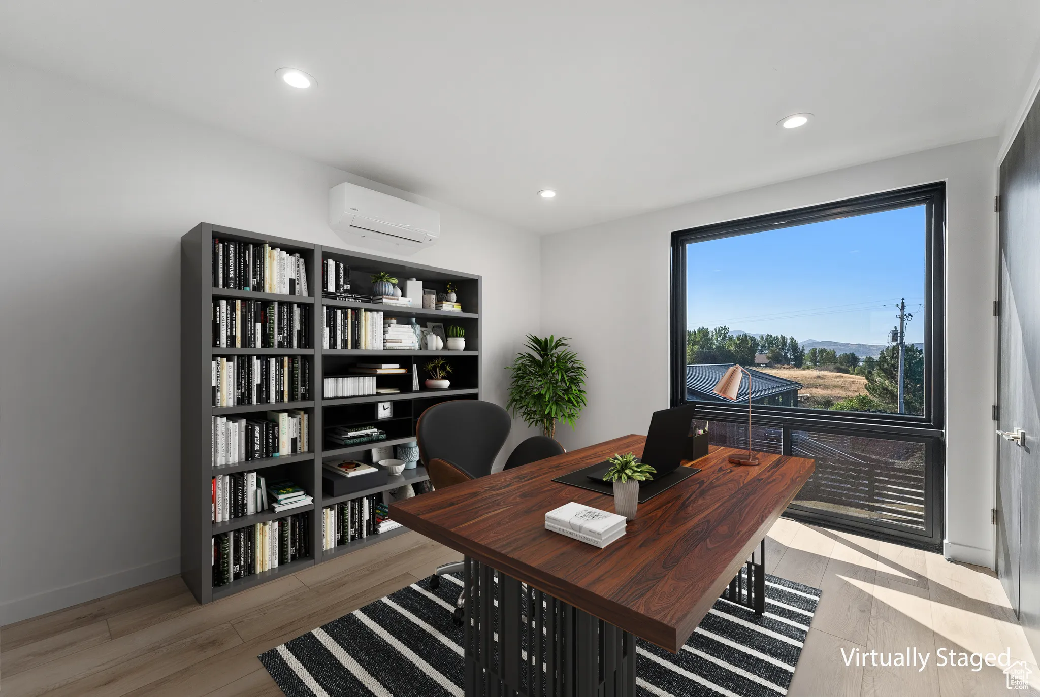 Home office with light wood-type flooring and a wall mounted AC