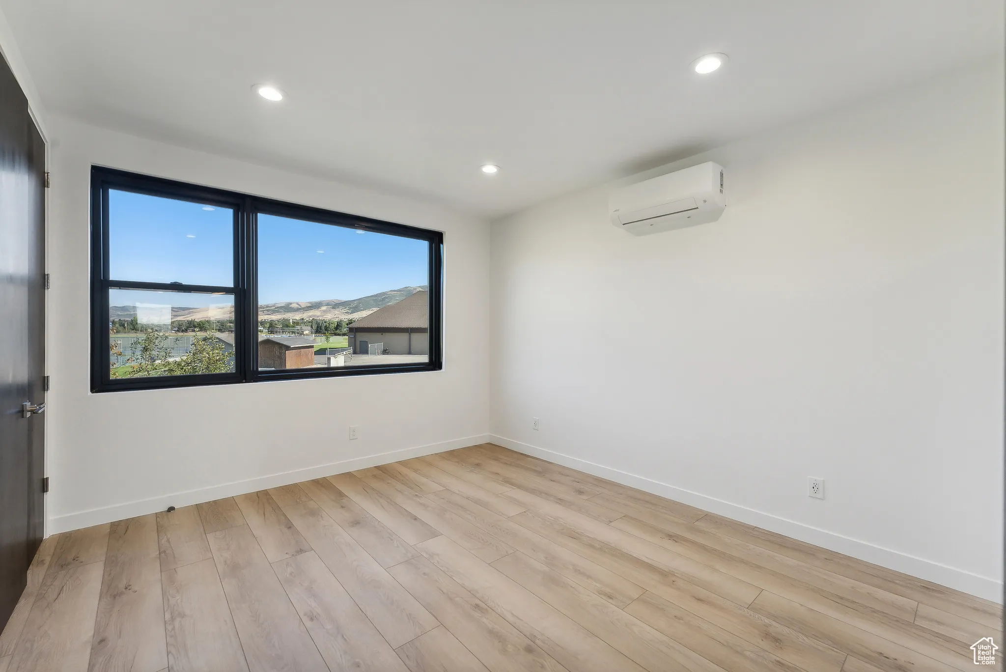 Spare room featuring light hardwood / wood-style flooring and a wall unit AC