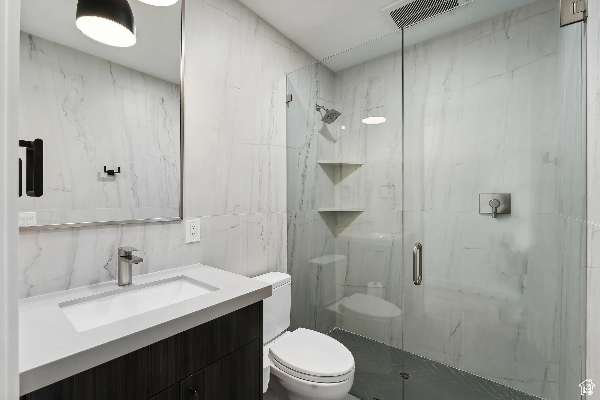Bathroom featuring tile walls, an enclosed shower, vanity, and toilet