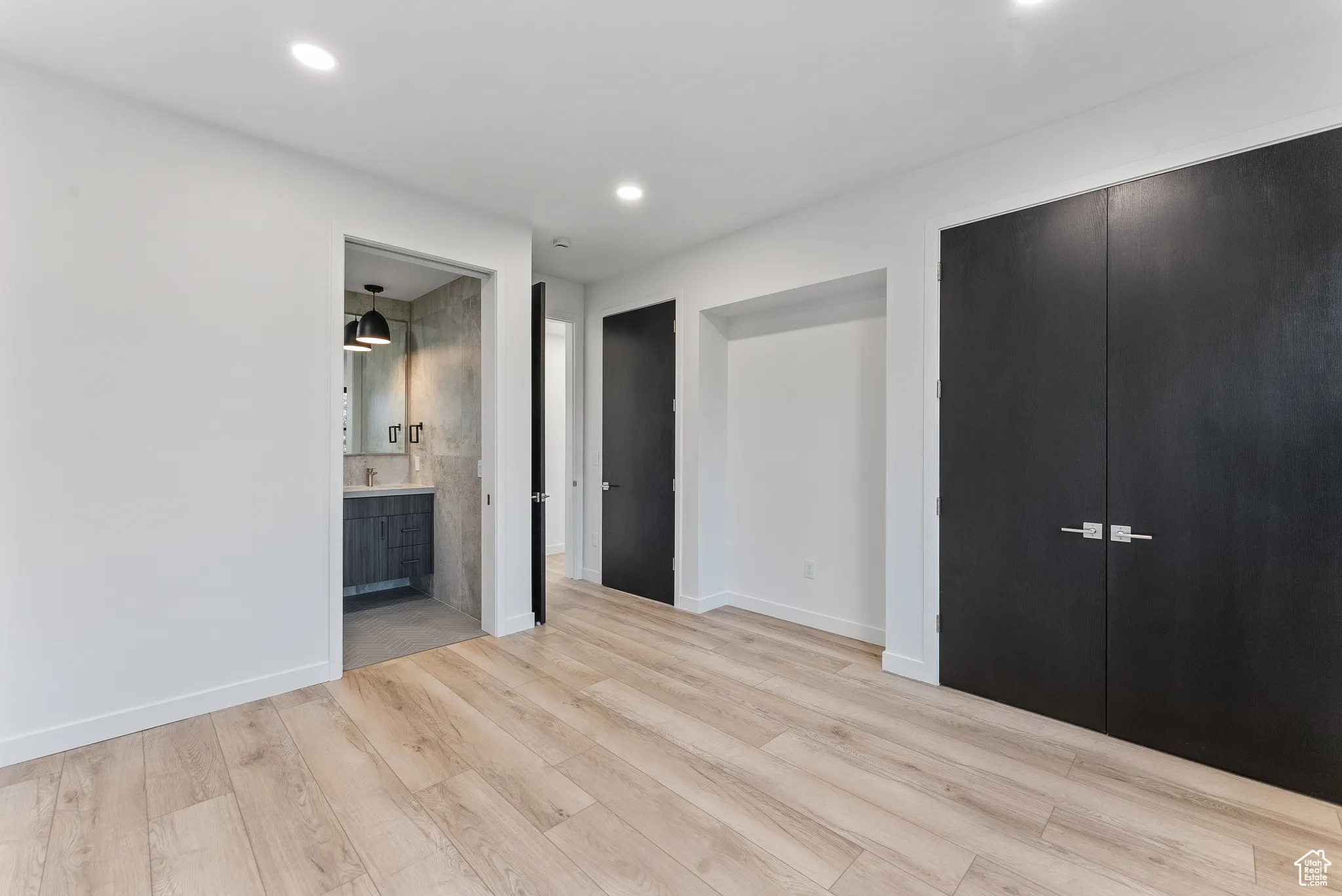 Unfurnished bedroom with connected bathroom, a closet, and light wood-type flooring