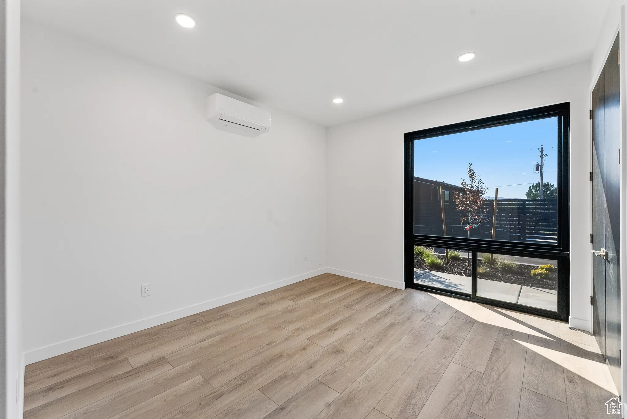 Spare room featuring light wood-type flooring and a wall mounted AC
