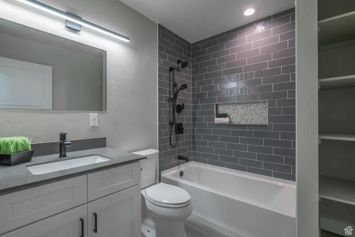 Full bathroom featuring vanity, tiled shower / bath combo, and toilet