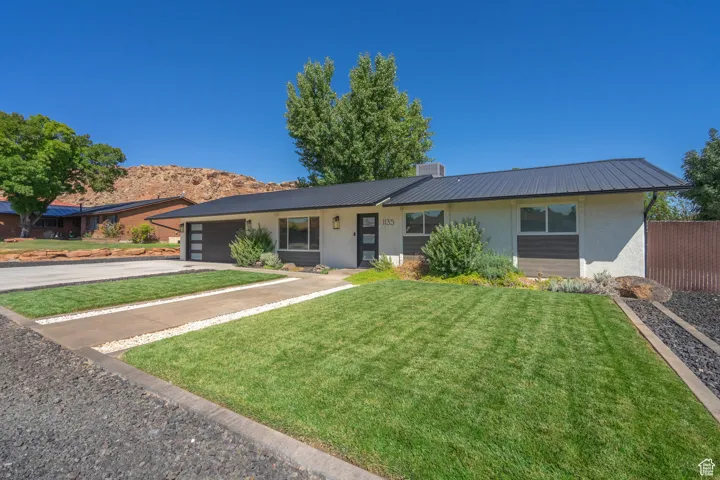 Single story home with a garage and a front lawn