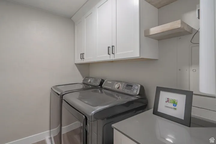 Washroom with cabinets, hardwood / wood-style floors, and independent washer and dryer