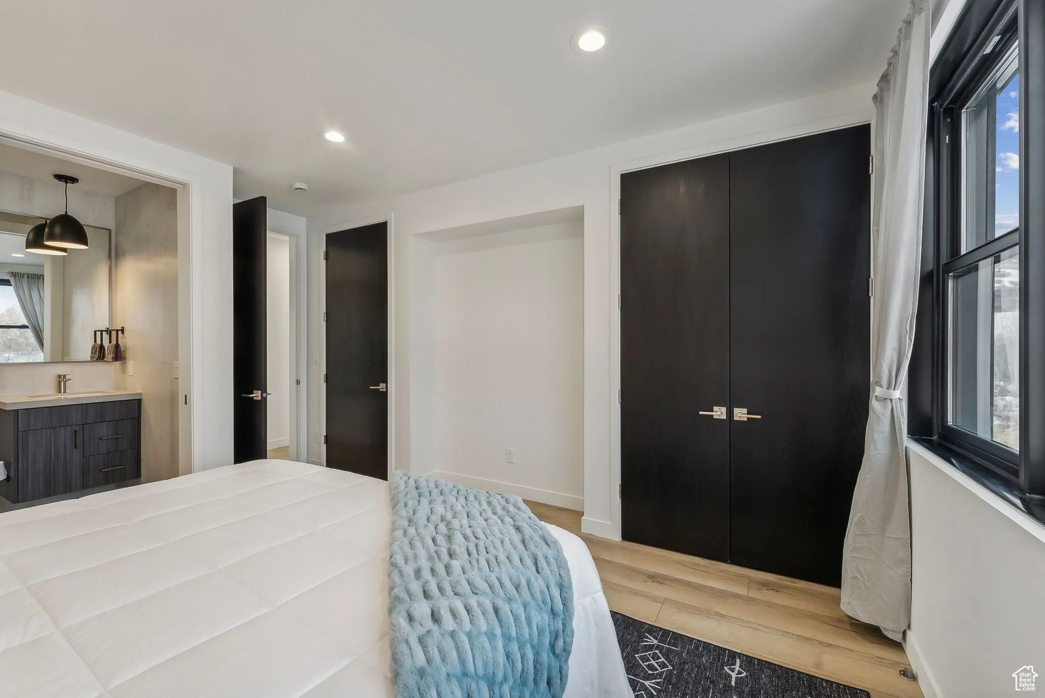 Bedroom featuring a closet, connected bathroom, hardwood / wood-style flooring, and multiple windows