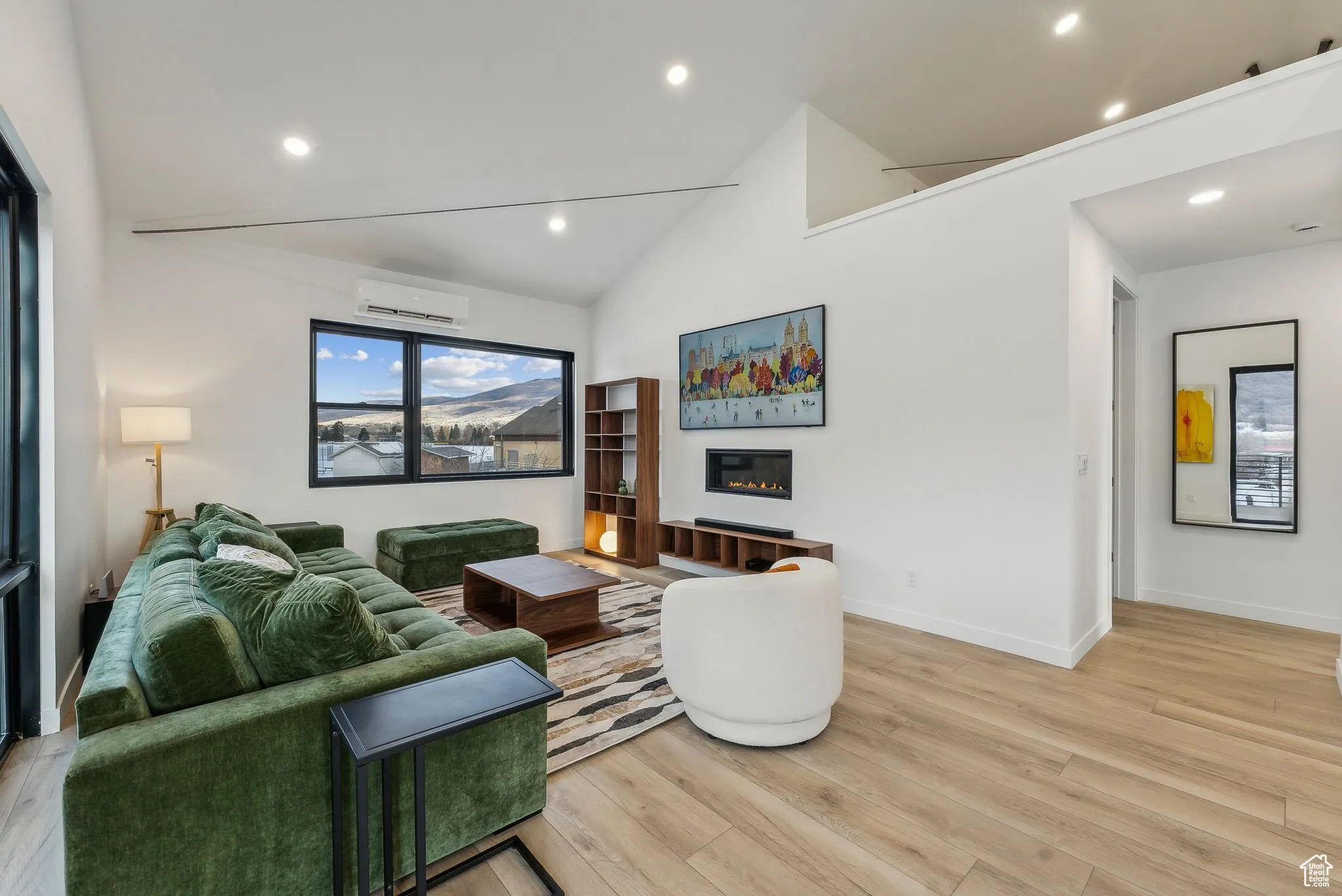 Living room featuring an AC wall unit, high vaulted ceiling, and light hardwood / wood-style flooring