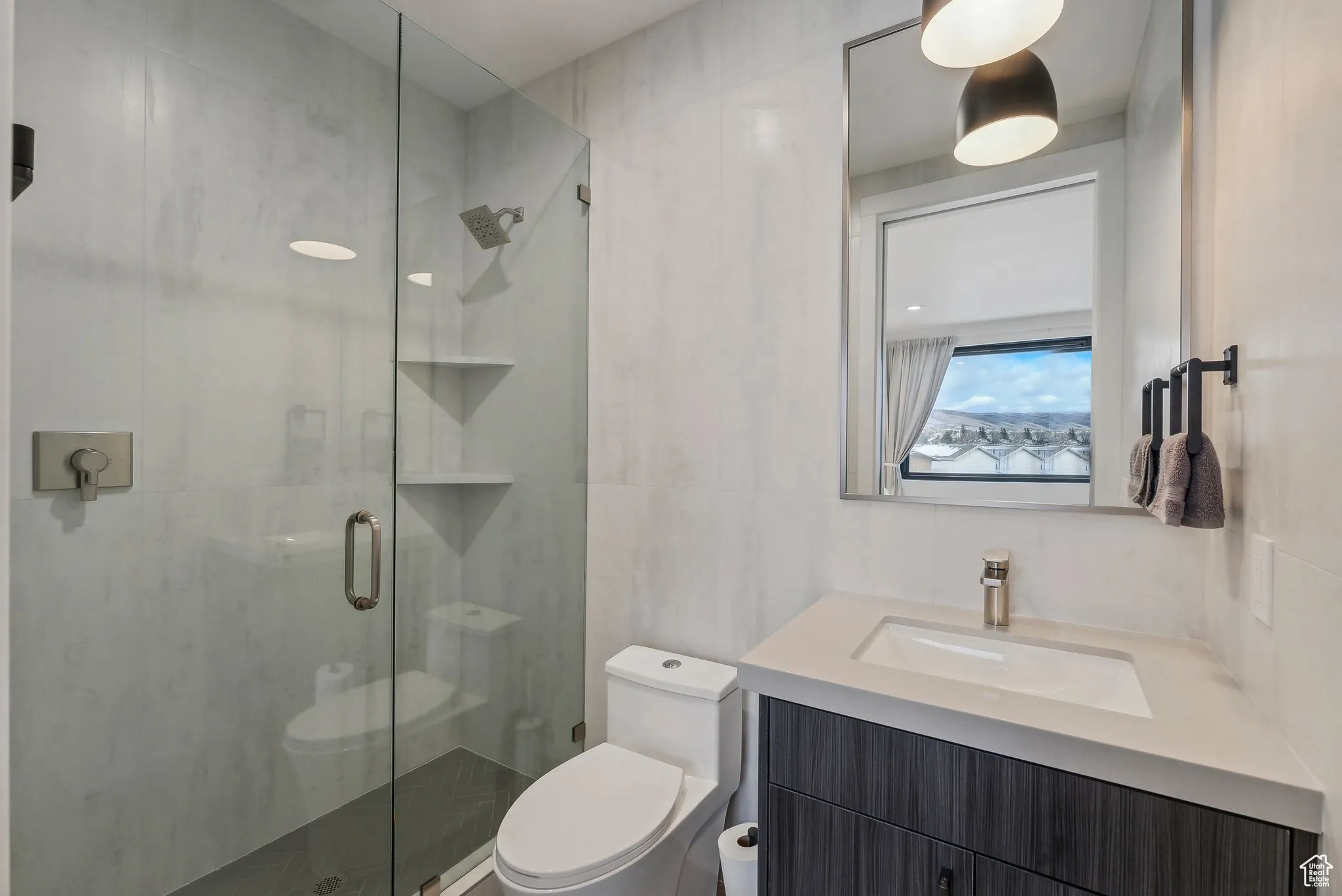Bathroom featuring a shower with door, vanity, tile walls, and toilet