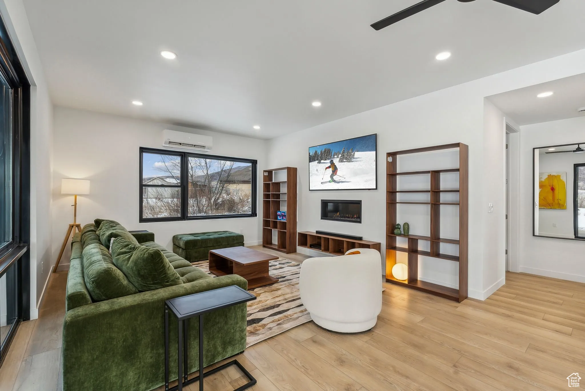 Living room with a wall mounted AC, ceiling fan, and light wood-type flooring