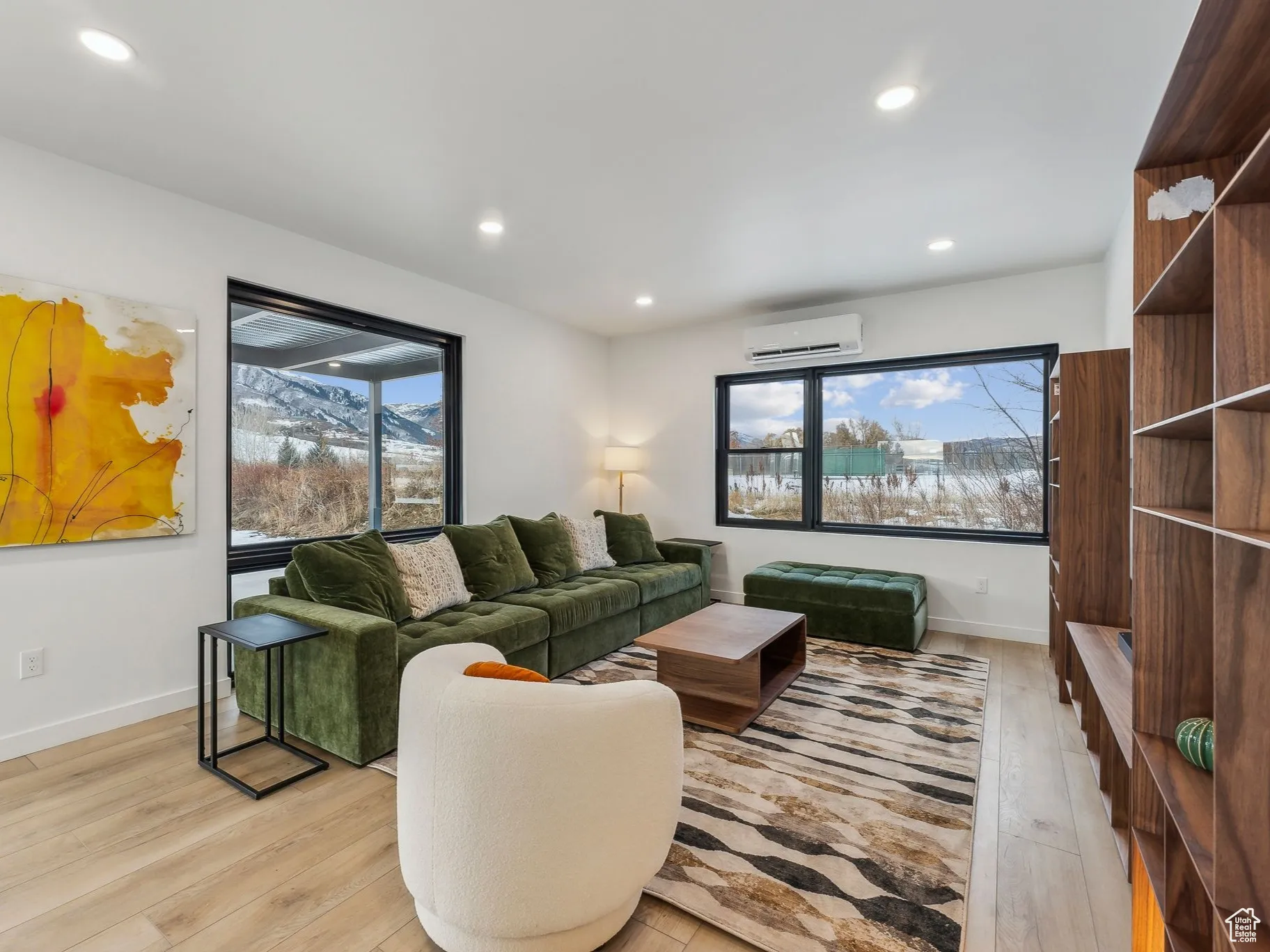 Living room with light hardwood / wood-style flooring, an AC wall unit, and a healthy amount of sunlight