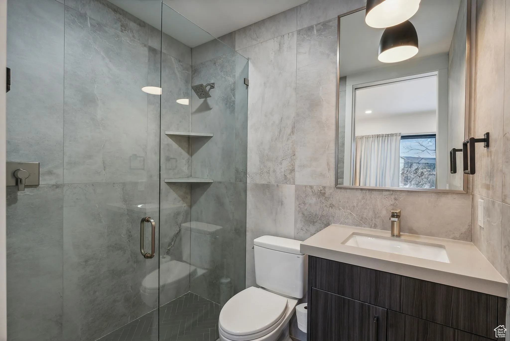 Bathroom with vanity, toilet, tile walls, and a shower with shower door