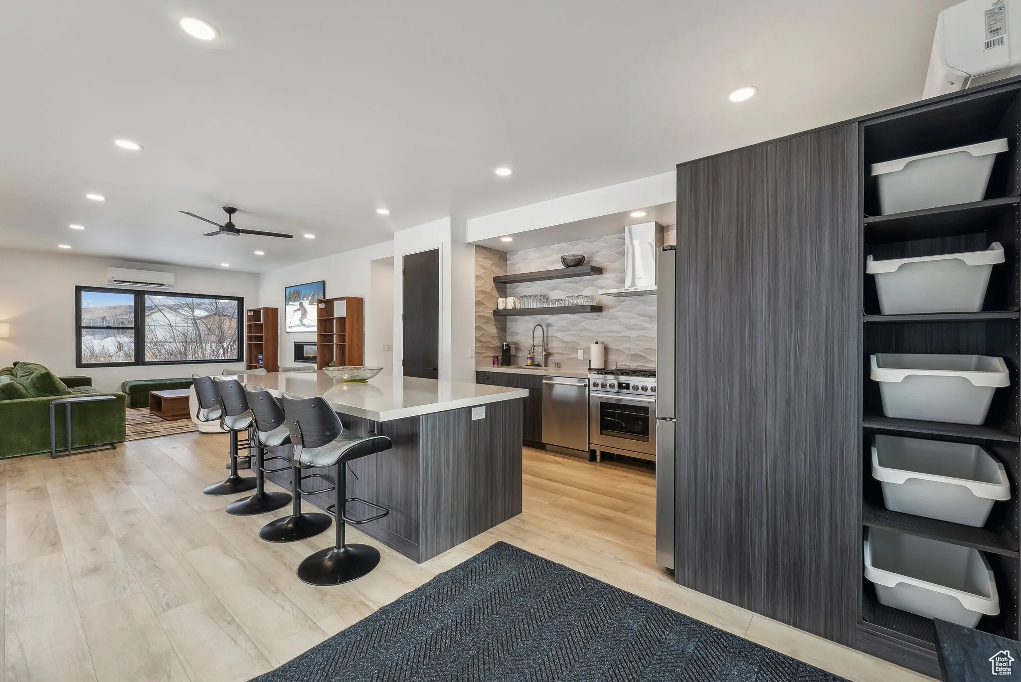 Kitchen featuring a center island, decorative backsplash, light wood-type flooring, a wall mounted AC, and a kitchen bar