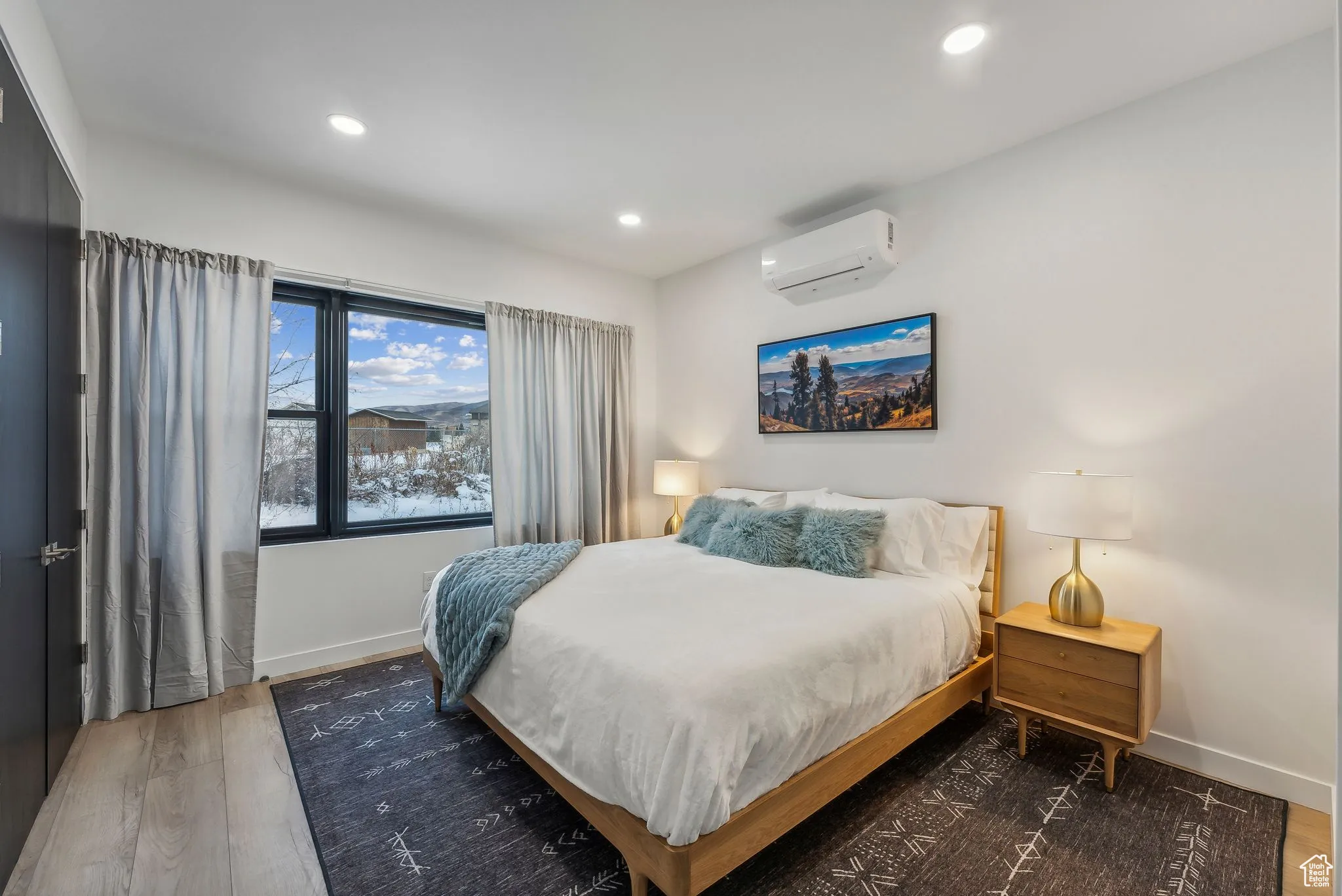 Bedroom with a wall mounted air conditioner and dark wood-type flooring