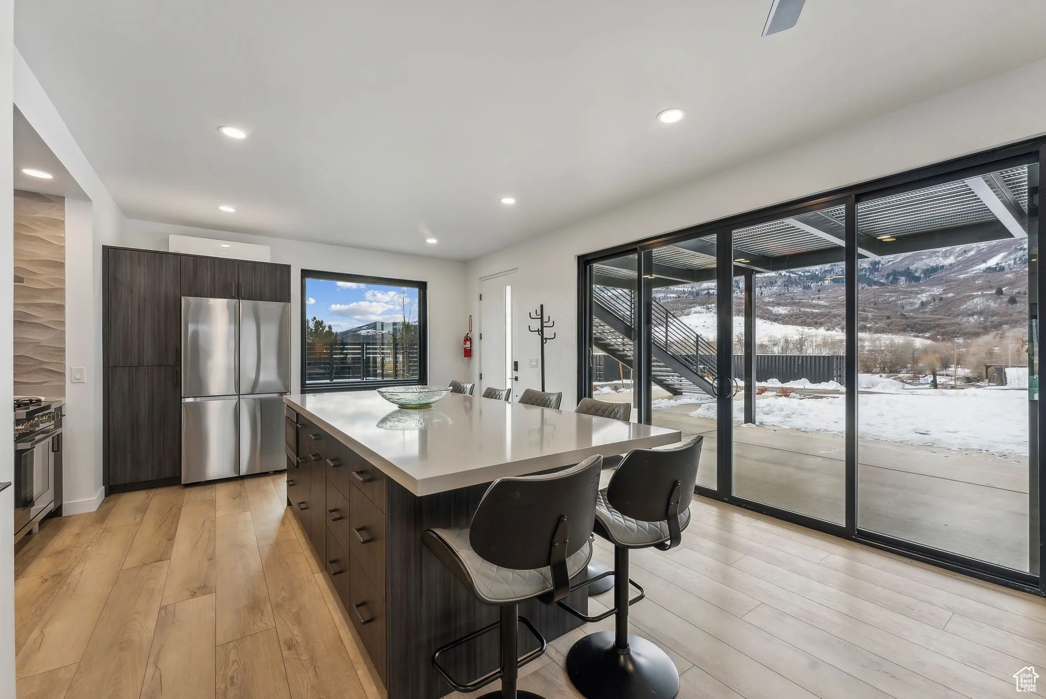 Kitchen with appliances with stainless steel finishes, light wood-type flooring, a kitchen island, and dark brown cabinetry