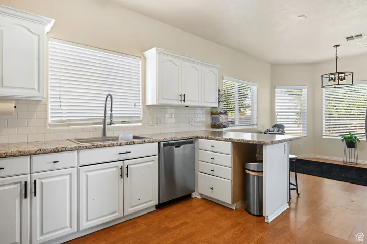 Kitchen featuring dishwasher, light hardwood / wood-style floors, sink, and white cabinetry
