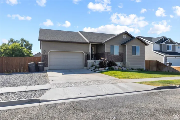 Single story home featuring a front yard, an attached garage, fence, and driveway