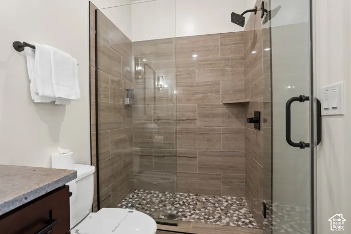 A tiled walk-in shower with a glass door and pebble floor.