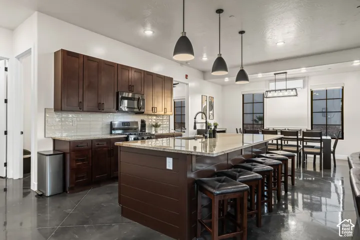 Pendant lights hang over a long granite island with bar seating for the whole group.