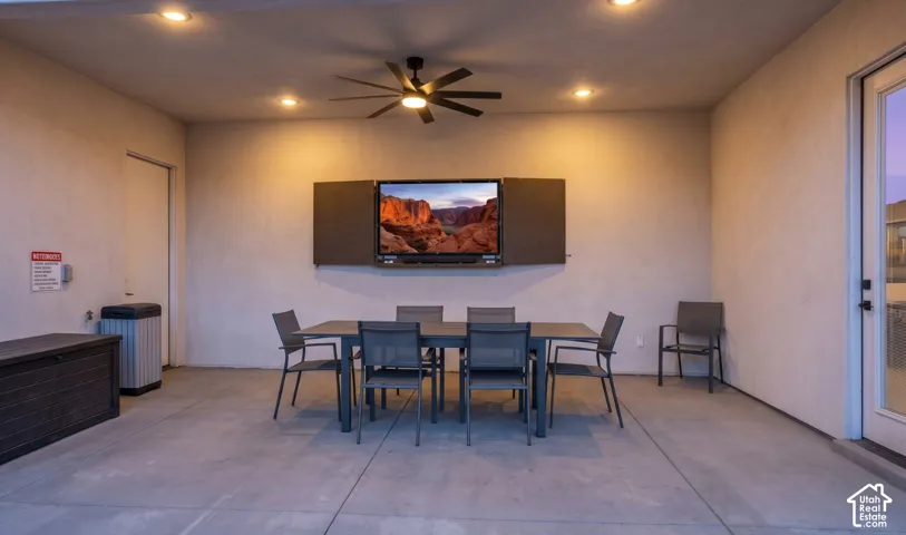 The covered patio has outdoor dining, a ceiling fan, and a mounted TV, right next to the pool.
