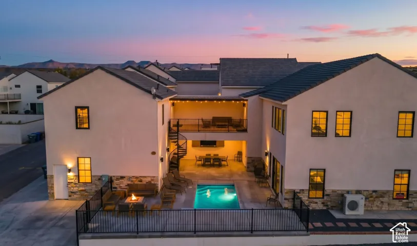 At dusk, the pool, covered patio, and upper deck light up the backyard.