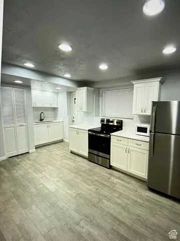 2nd Kitchen featuring appliances with stainless steel finishes, white cabinets, and LVP flooring in basement
