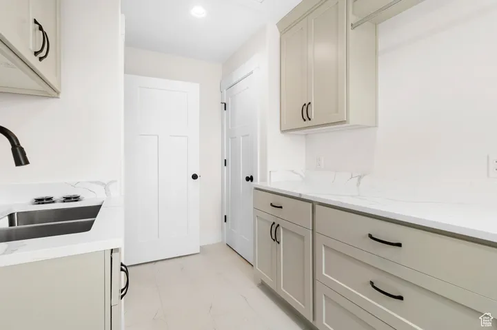 Kitchen with light stone countertops, marble finish floor, a sink, and recessed lighting