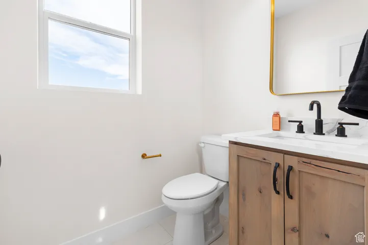Bathroom with toilet, tile patterned flooring, baseboards, and vanity
