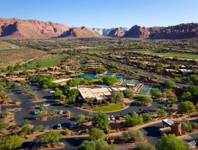 Bird's-eye view of the community showcasing tennis courts, a golf course, and breathtaking mountain scenery.