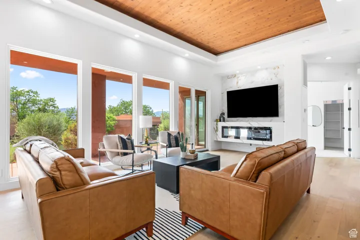 Living room with light hardwood / wood-style flooring, a tray ceiling, and wood ceiling