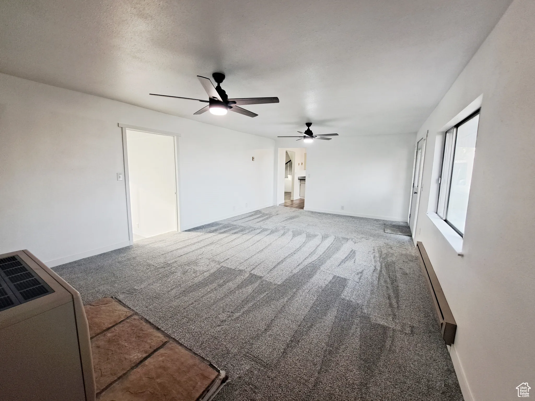 Living room featuring a textured ceiling, new carpet, new paint, and ceiling fan