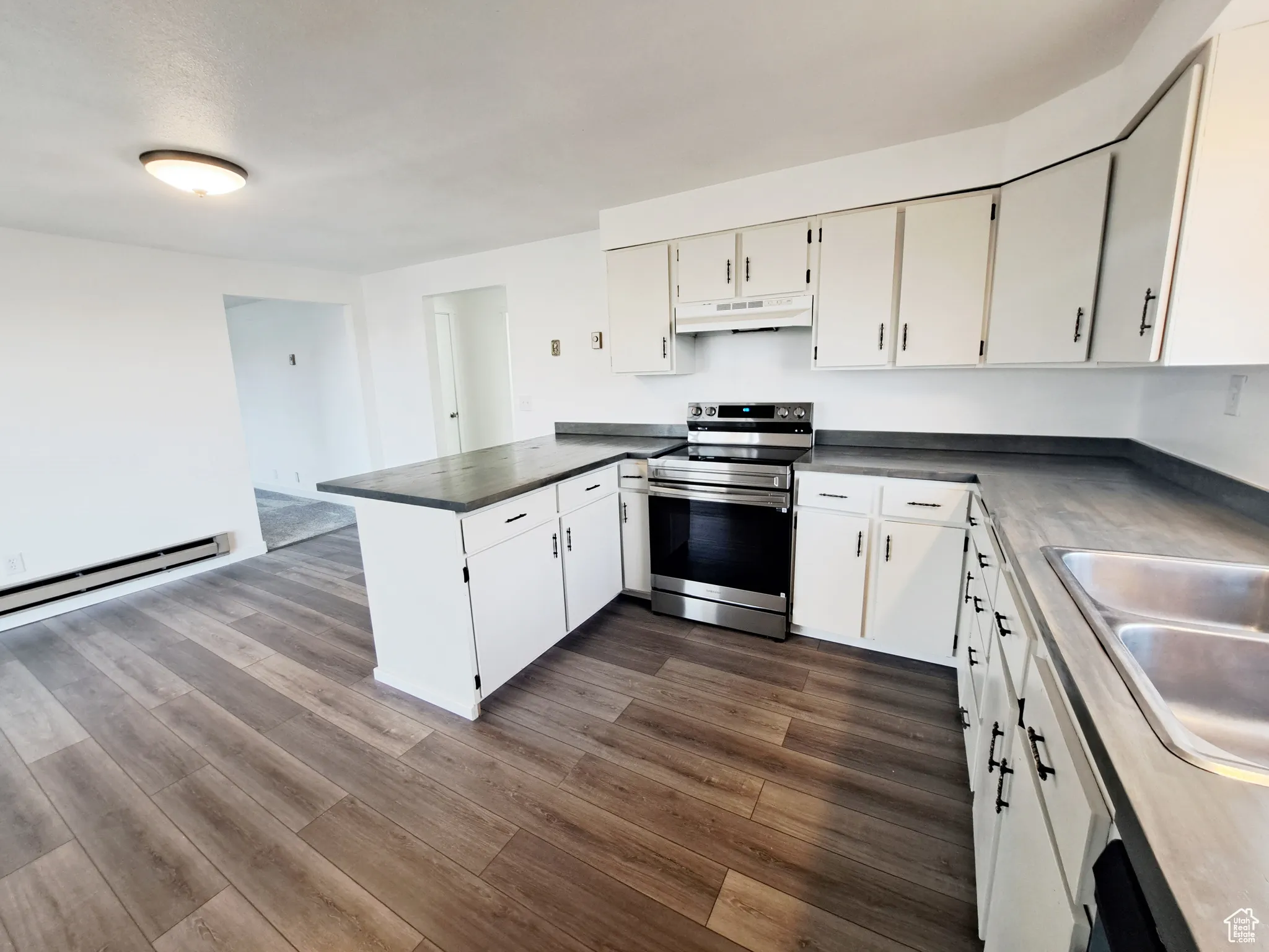 Kitchen featuring electric stove, kitchen peninsula, sink, and white cabinets, New LVP flooring, New Appliances, New Paint, New Butcher Block Countertops