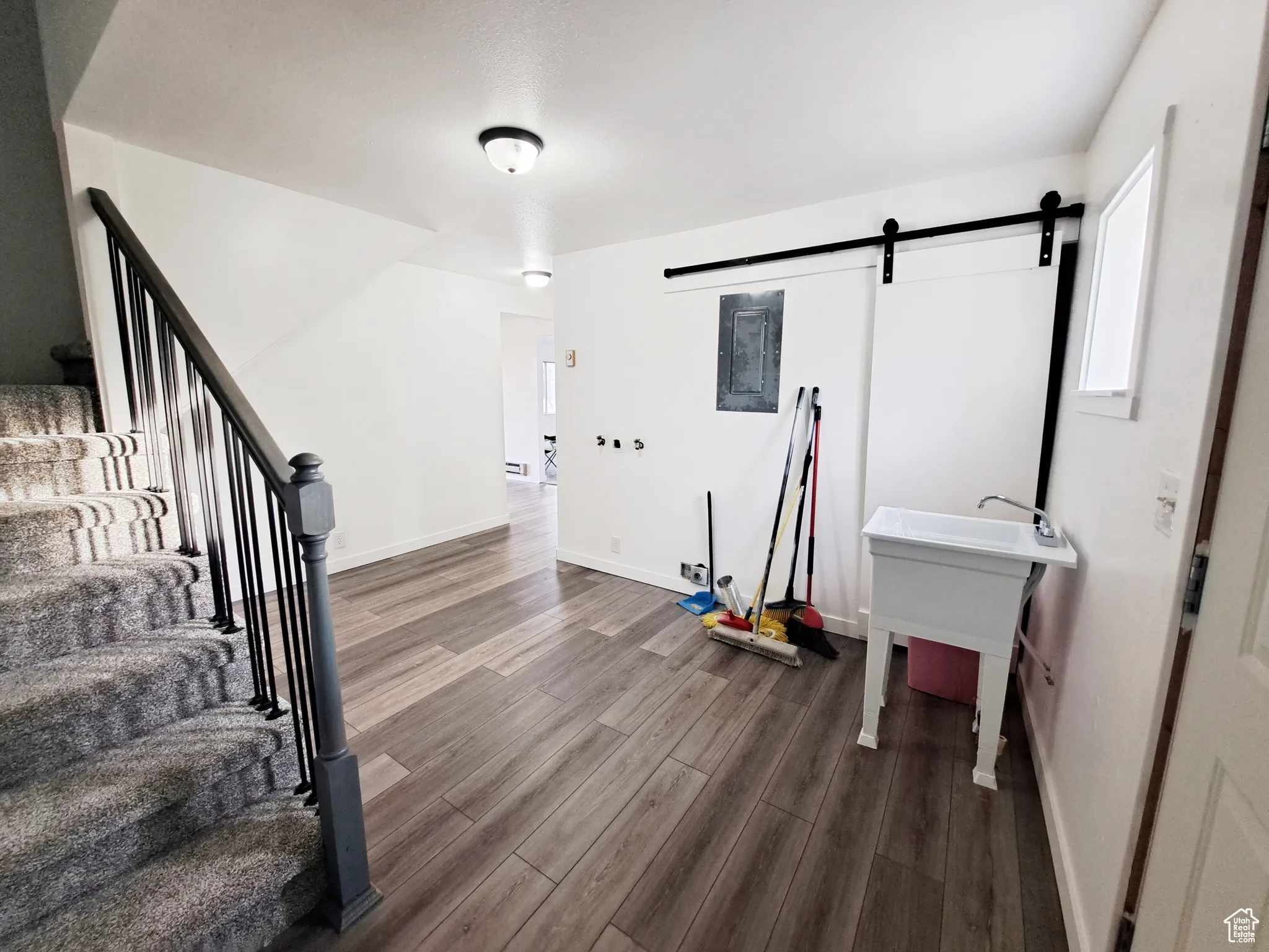 Laundry/ Mud Room/Foyer with New LVP flooring, New Paint, New Doors, New Carpet, New Railing, New barn door, and sink