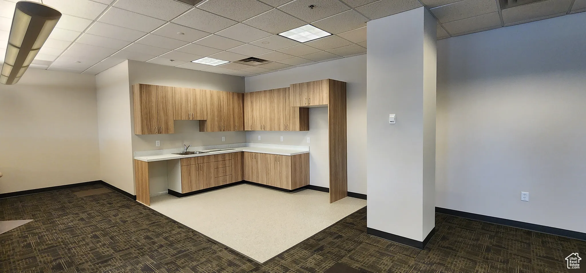 Kitchen with dark carpet, a paneled ceiling, and sink