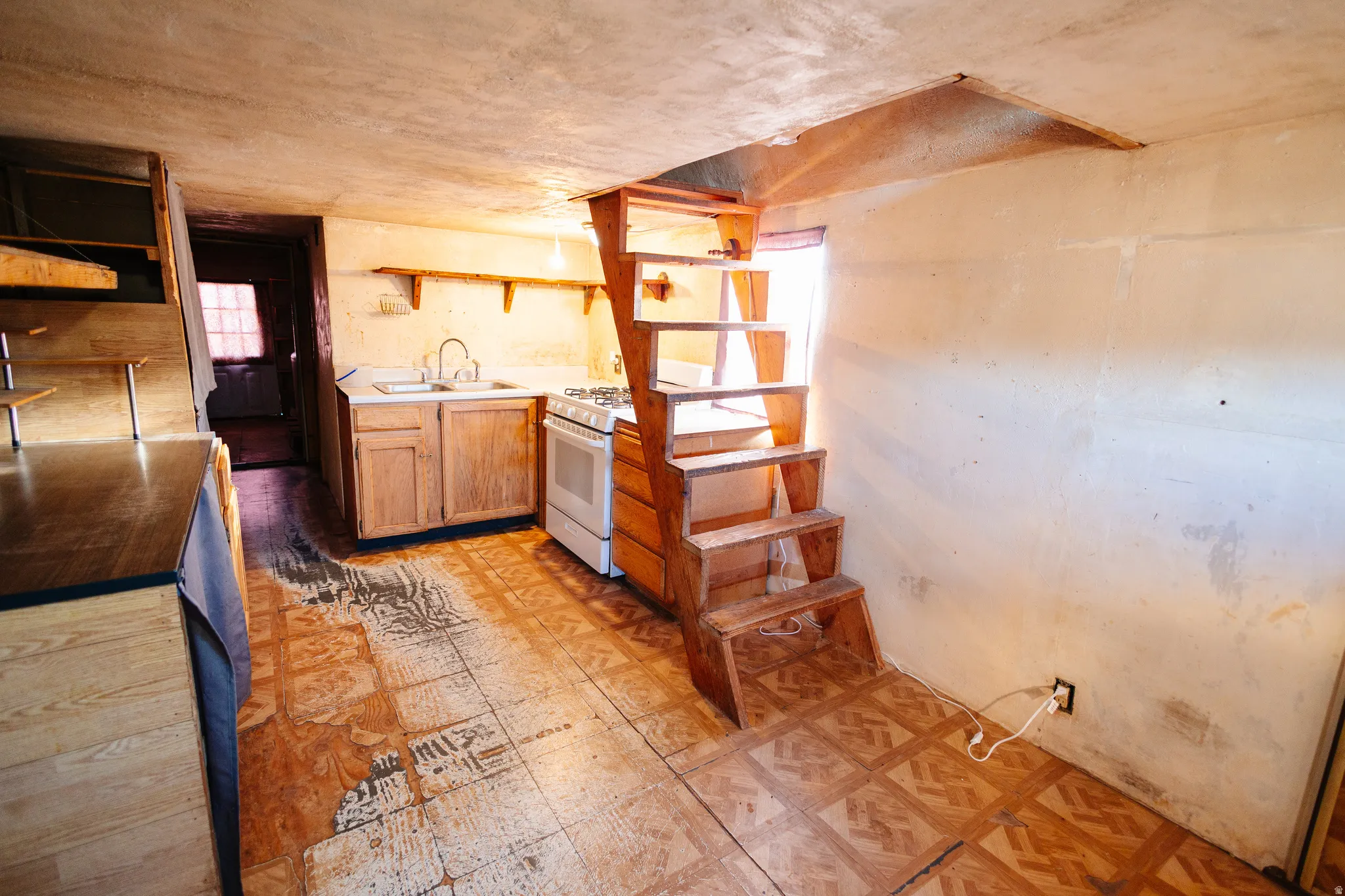 Kitchen featuring open shelves, light countertops, white gas stove, and light flooring
