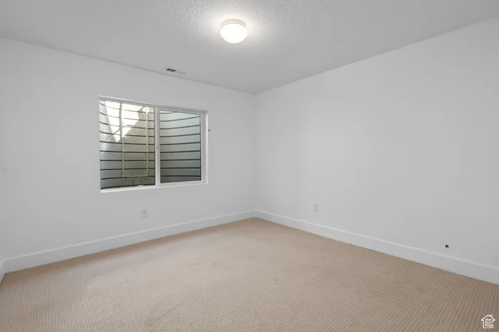 Spare room featuring carpet floors and a textured ceiling