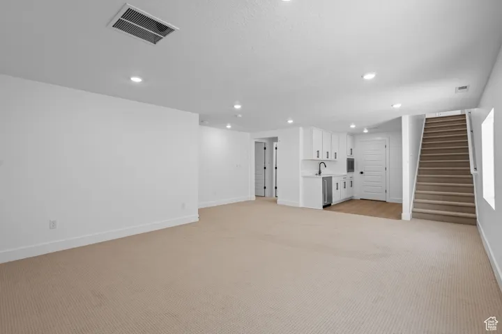 Unfurnished living room featuring light colored carpet and sink