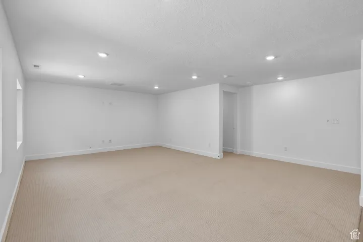 Empty room featuring light carpet and a textured ceiling
