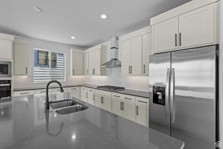 Kitchen with tasteful backsplash, sink, wall chimney exhaust hood, and stainless steel appliances