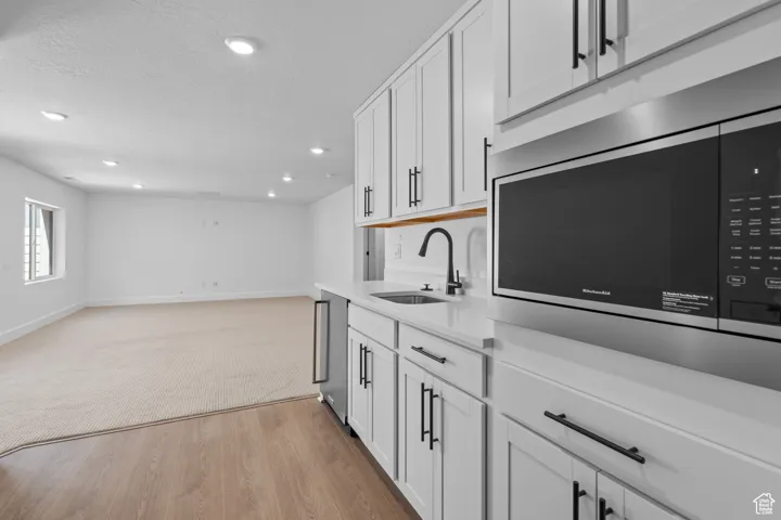 Kitchen featuring white cabinetry, sink, stainless steel appliances, light hardwood / wood-style flooring, and a textured ceiling