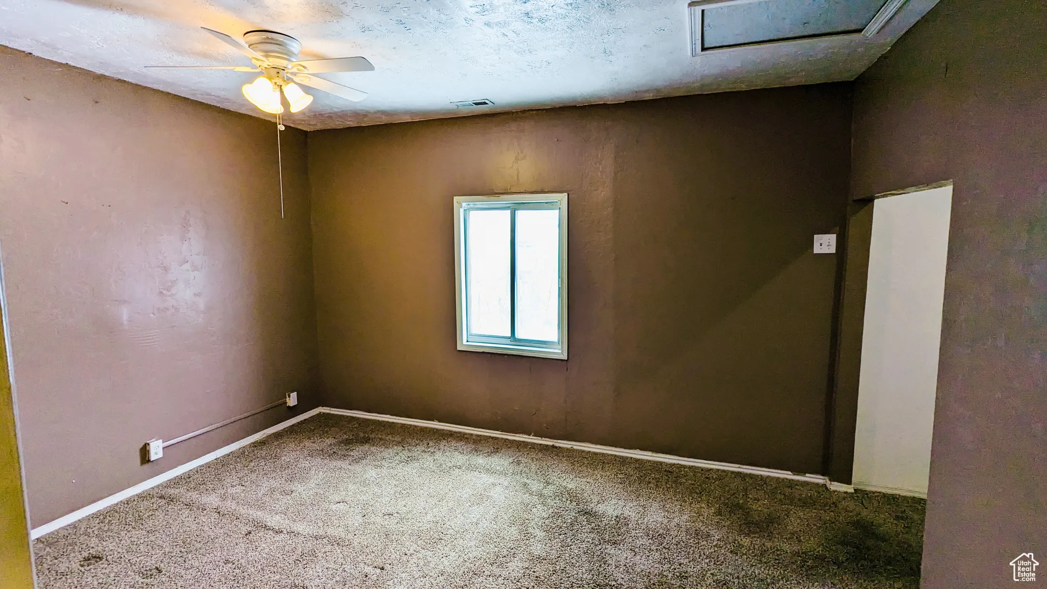 Carpeted empty room with ceiling fan and a textured ceiling