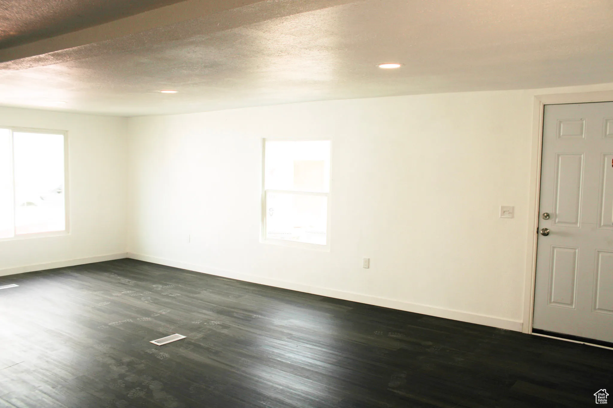 Spare room with a textured ceiling, a healthy amount of sunlight, and dark wood-type flooring