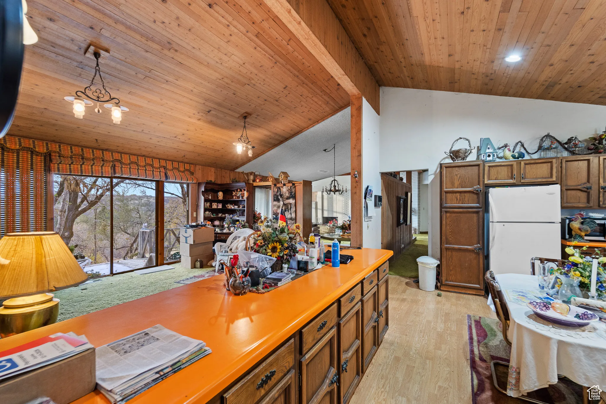 Kitchen with pendant lighting, lofted ceiling with beams, white refrigerator, and an inviting chandelier