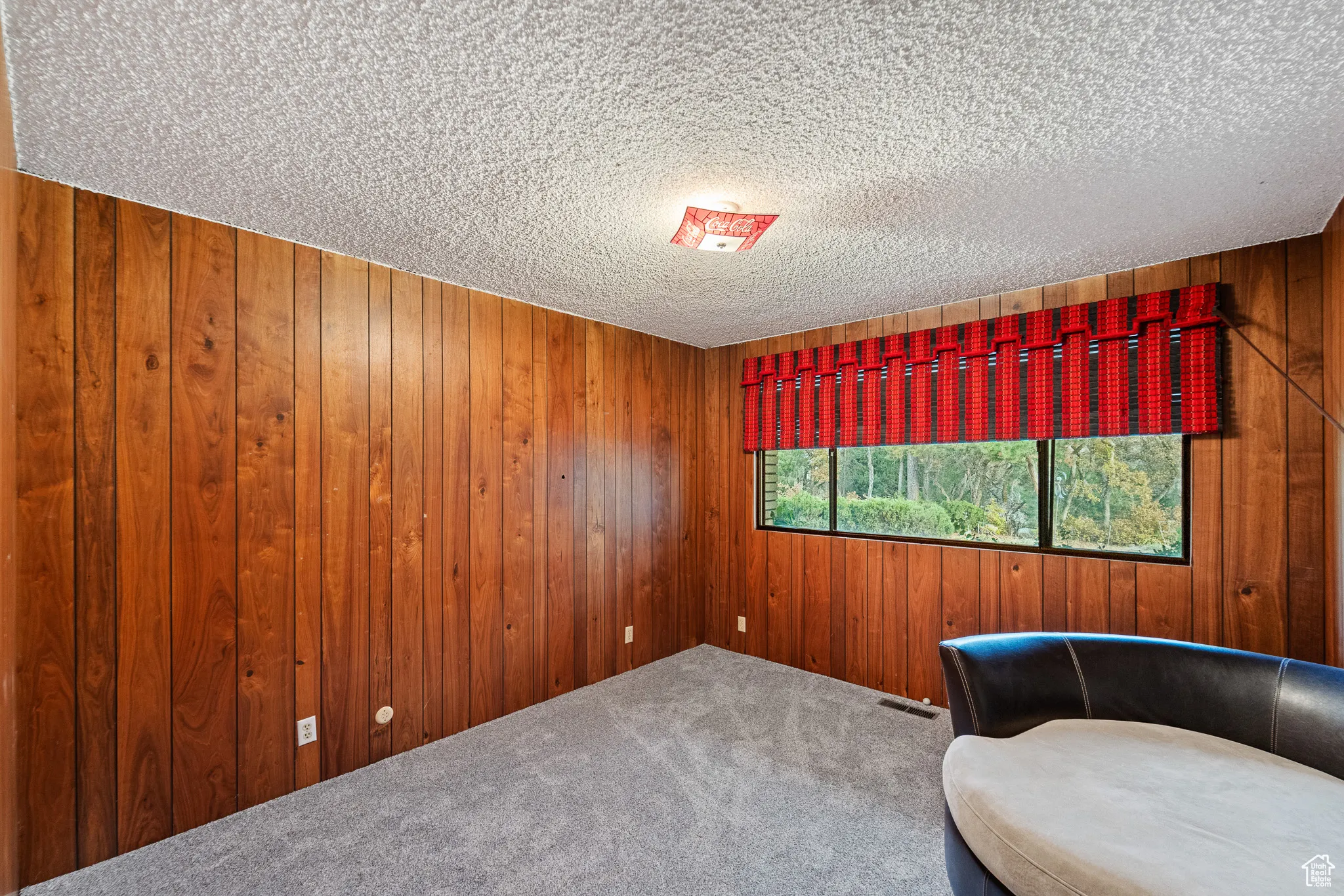 Unfurnished room featuring carpet flooring, a textured ceiling, and wood walls