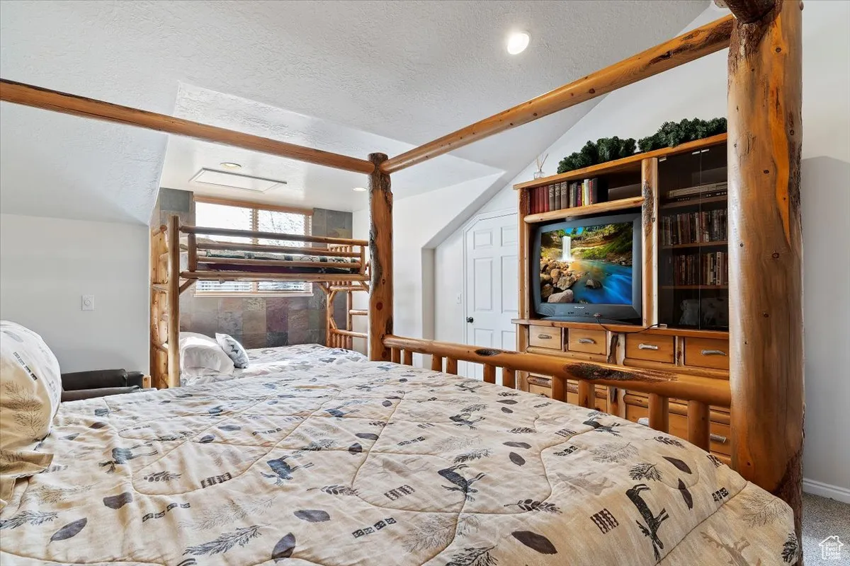 Bedroom featuring carpet flooring, a textured ceiling, and vaulted ceiling