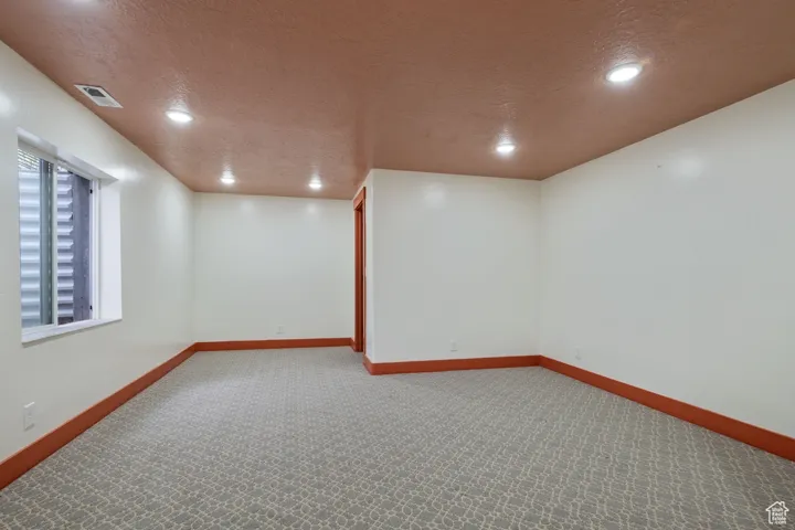 Basement featuring baseboards, visible vents, a textured ceiling, and carpet