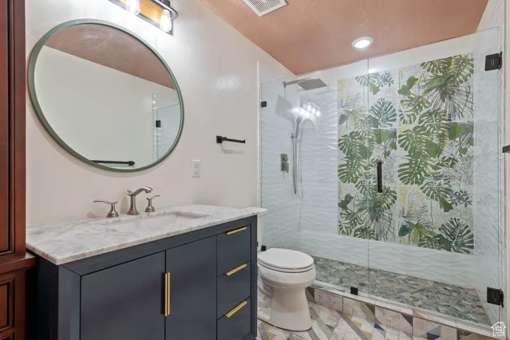 Full bathroom featuring visible vents, a shower stall, toilet, and vanity