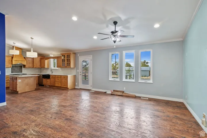 Unfurnished living room with recessed lighting, ornamental molding, a sink, baseboards, and a ceiling fan