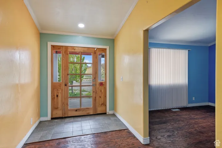Foyer entrance featuring wood finished floors, crown molding, and baseboards