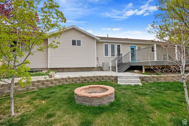 Back of property featuring a fire pit, a wooden deck, stairway, a yard, and central AC unit